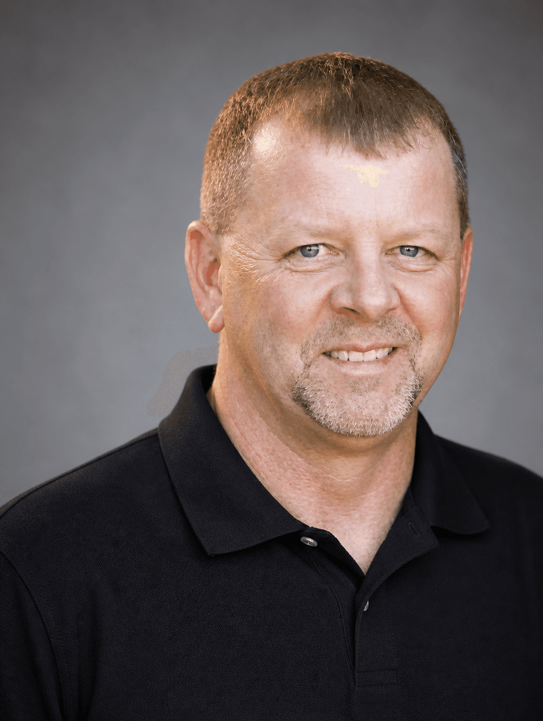 Middle-aged man with short brown hair and a goatee wearing a black polo shirt.