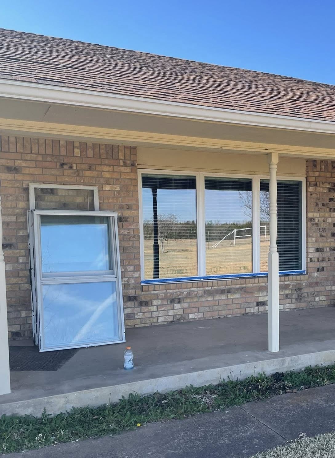 New window unit leaning against a brick wall next to a large installed window.